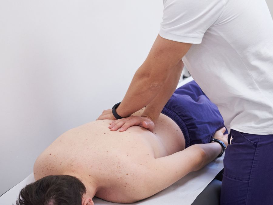 Fisioterapista assiste un paziente in esercizi terapeutici per migliorare mobilità e ridurre il dolore alla schiena.